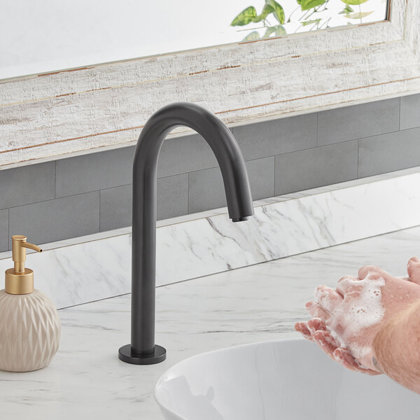 A person washing their hands with soap under a Waterloo matte black hands-free sensor faucet.
