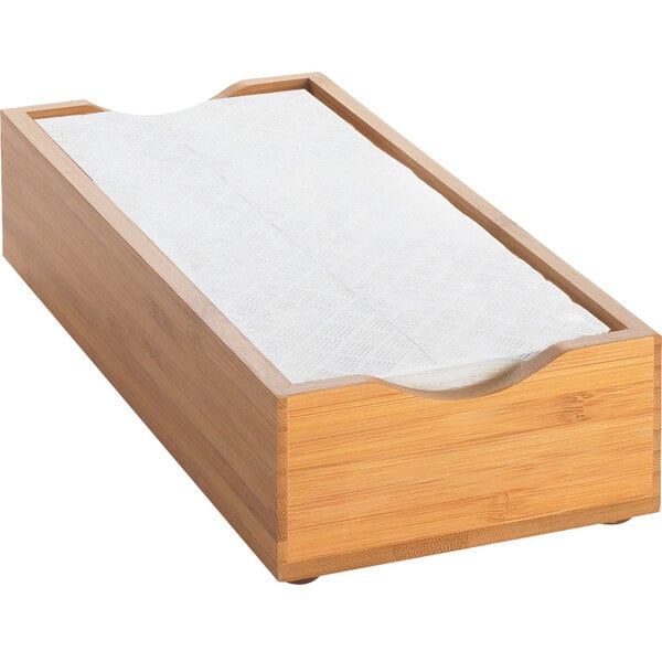 A bamboo napkin holder with a white napkin in it.