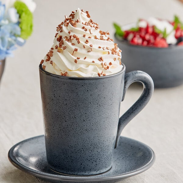 A close up of a cup of coffee with whipped cream and sprinkles in a Midnight Blue Matte stoneware mug.
