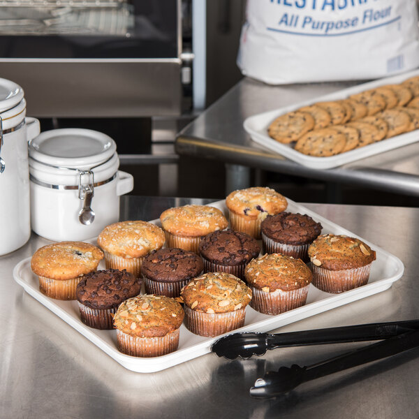 A Carlisle Pearl White fiberglass market tray with muffins on a counter.