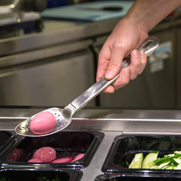 A person using a Vollrath perforated stainless spoon to serve food.