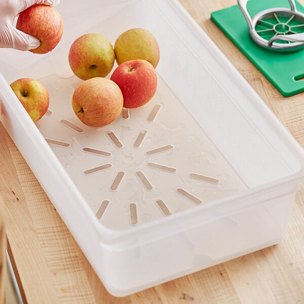 A person using a Vigor translucent plastic food pan drain tray to hold apples.