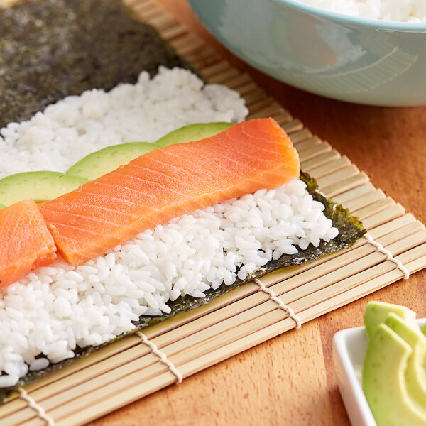 A bowl of sushi rice with a piece of salmon and avocado.