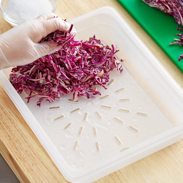 A gloved hand in a plastic Vigor drain tray with shredded red cabbage.