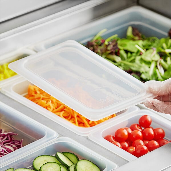A person using a Vigor translucent plastic container lid to cover a container of vegetables.