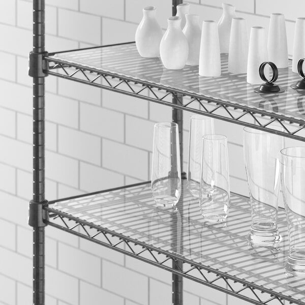 A white shelf with glass cups and vases on white Regency shelf liner.