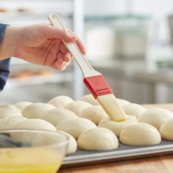 A person's hand using a Thermohauser pastry brush to brush dough.