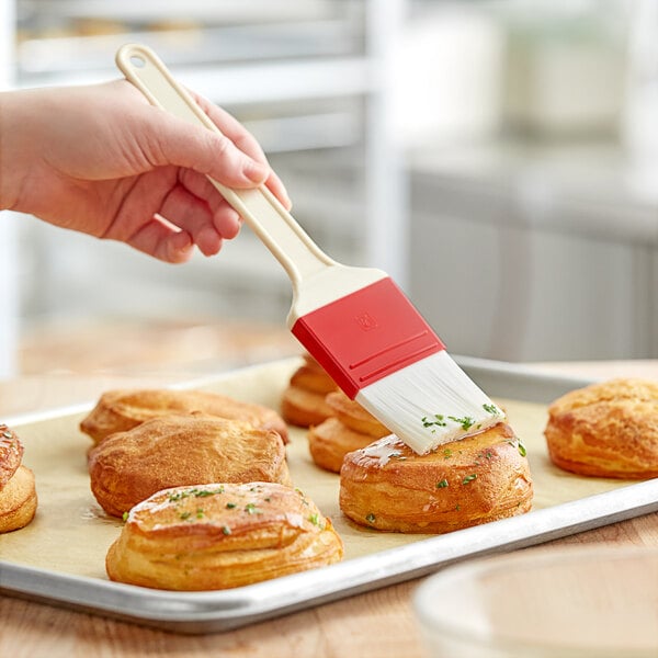 A hand holding a Choice pastry brush over pastries.