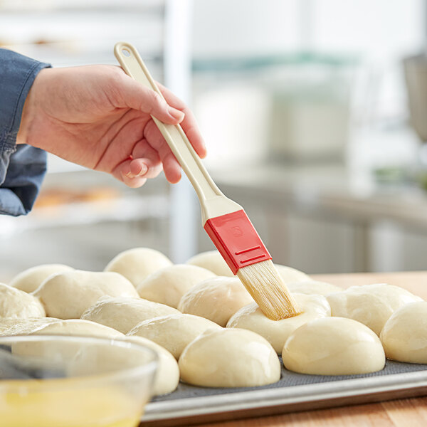 A person using a W Natural Bristle pastry brush to brush dough.