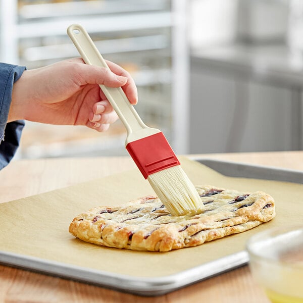 A hand holding a pastry with a Thermohauser pastry brush.