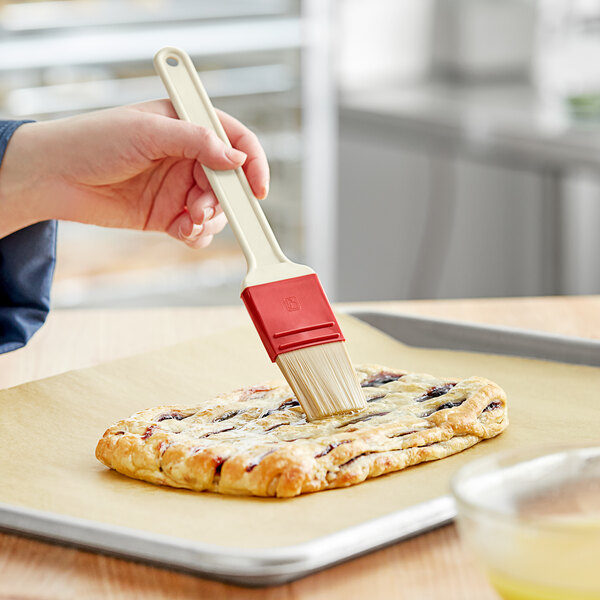 A person using a Choice pastry brush to glaze a pastry.