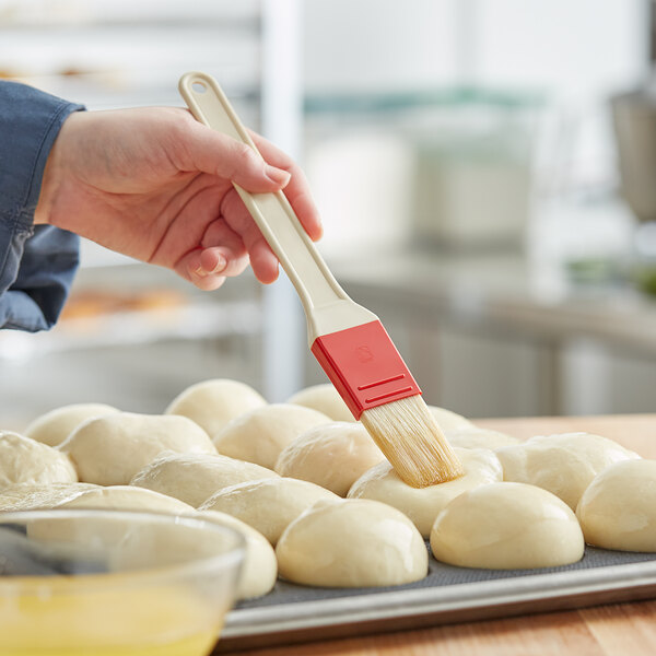 A person using a Choice natural bristle pastry / basting brush to brush dough.