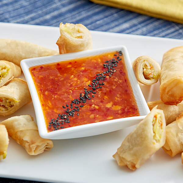 Fried spring rolls on a plate with a bowl of Ashoka Hot and Sweet Chilli Dipping Sauce.
