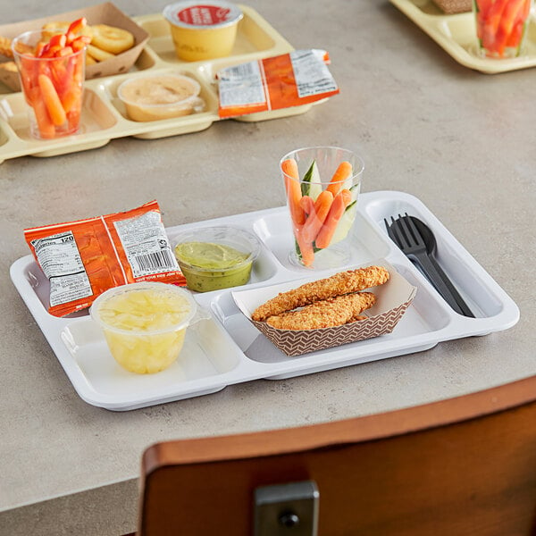 A right handed heavy-duty white melamine tray with 6 compartments holding a variety of food, including a yellow container of carrots.