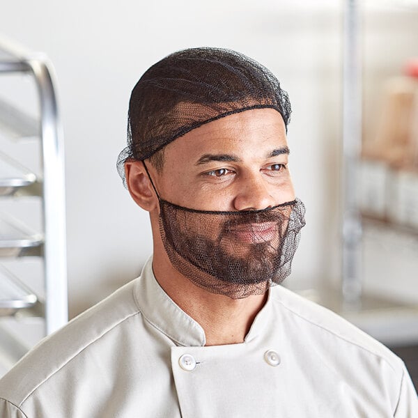 A man in a chef's uniform wearing a black net over his hair.