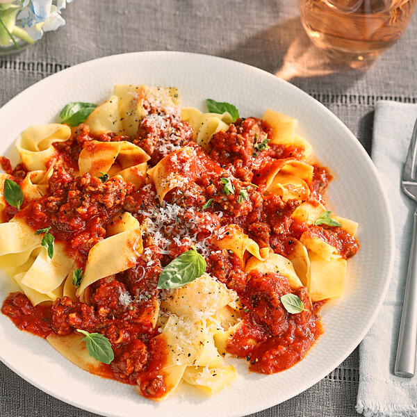 A plate of pasta with Vine Ripe Whole Peeled Tomatoes in Juice and meat sauce and cheese.