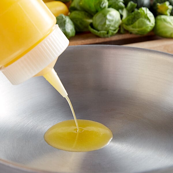 A person pouring yellow liquid from a 1 gallon bottle into a pan.