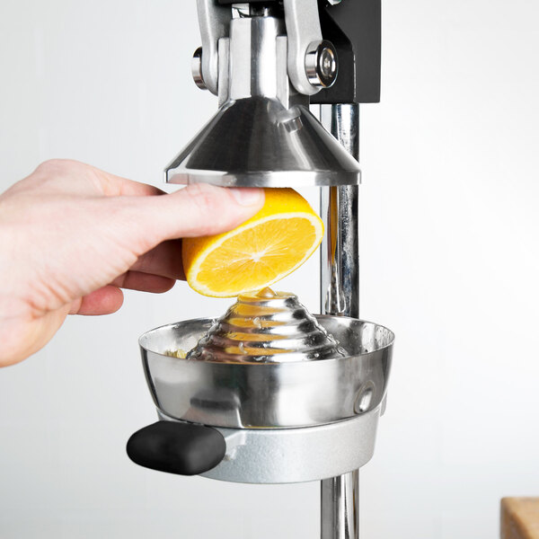 A person's hand squeezing a lemon into a white Choice cone juicer.