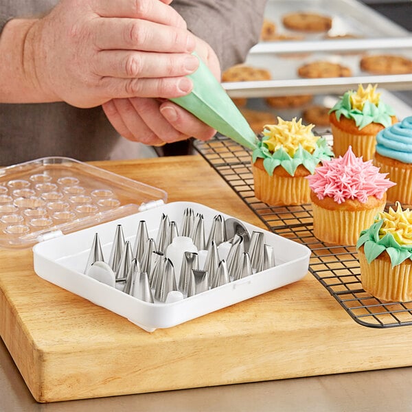 A person using a Choice stainless steel piping tip to decorate cupcakes.