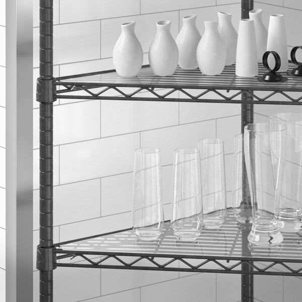 A Regency shelf with triangle shelf liner holding vases and glasses.