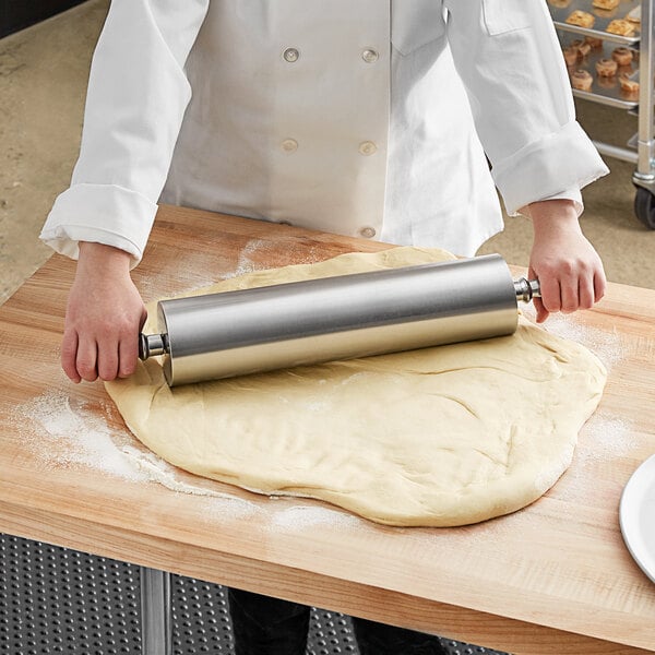 A person rolling dough with a Choice aluminum rolling pin.