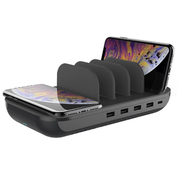 A black Kantek wireless desktop charging station with three cell phones charging.
