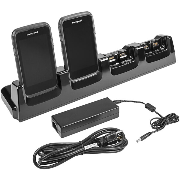 A black Honeywell charging cradle with four mobile computers sitting in it.