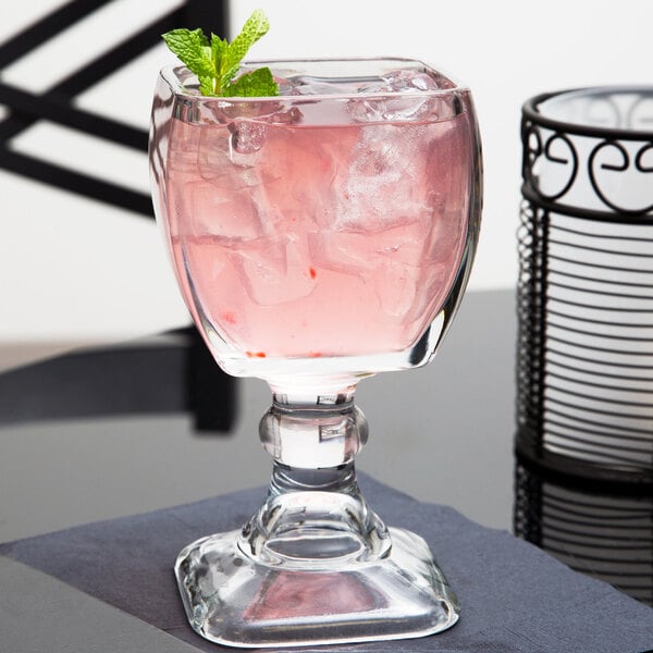A Libbey Suprema Schooner glass with a pink drink and a mint leaf on the stem.