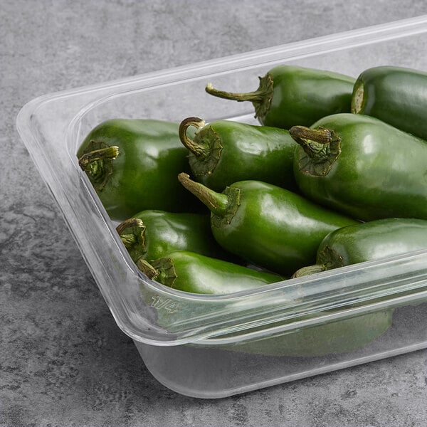 A plastic container with fresh jalapeno peppers.
