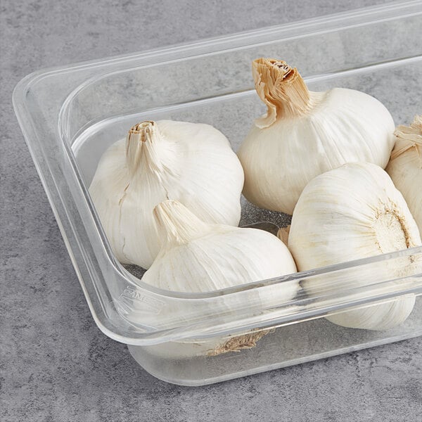 A clear plastic container with fresh white garlic cloves inside.