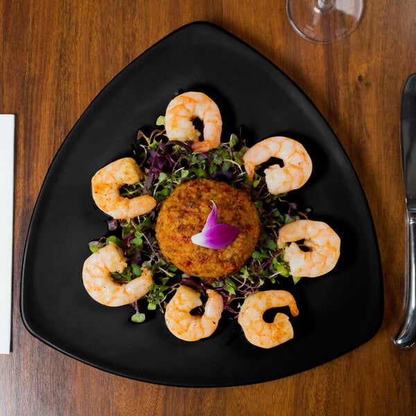 A GET black triangle melamine plate with shrimp on it.