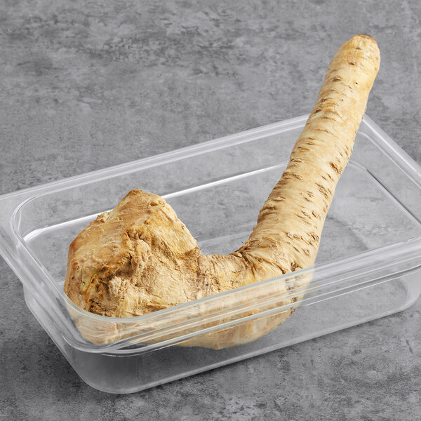 A whole horseradish root in a plastic container.