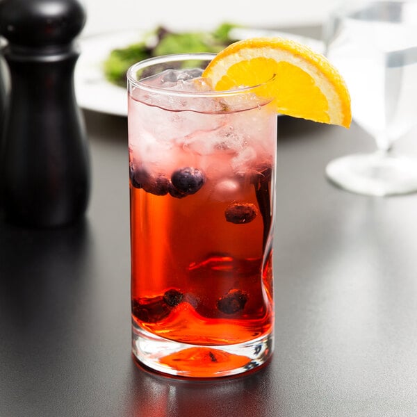 A Libbey cooler glass filled with red liquid and a slice of orange on the rim.