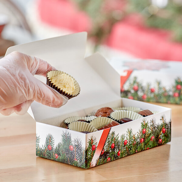 A gloved hand holding a 1 lb. Bow and Berries print candy box with a cupcake inside.