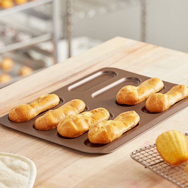 A Gobel eclair mold on a table with pastries.