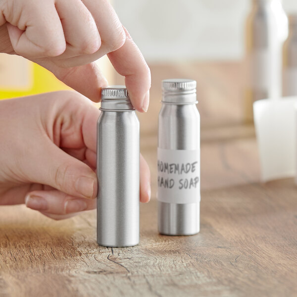 A person holding a silver aluminum bottle with a lid.