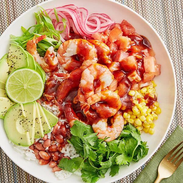 A bowl of shrimp, rice, and vegetables with Sauce Craft Taco Sauce on a table.