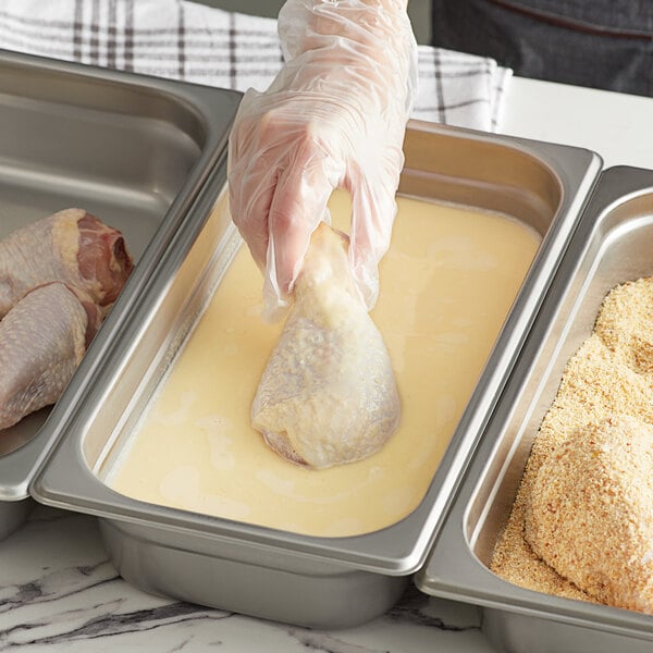 A person using Golden Dipt Pre-Dip Batter Mix to bread chicken.