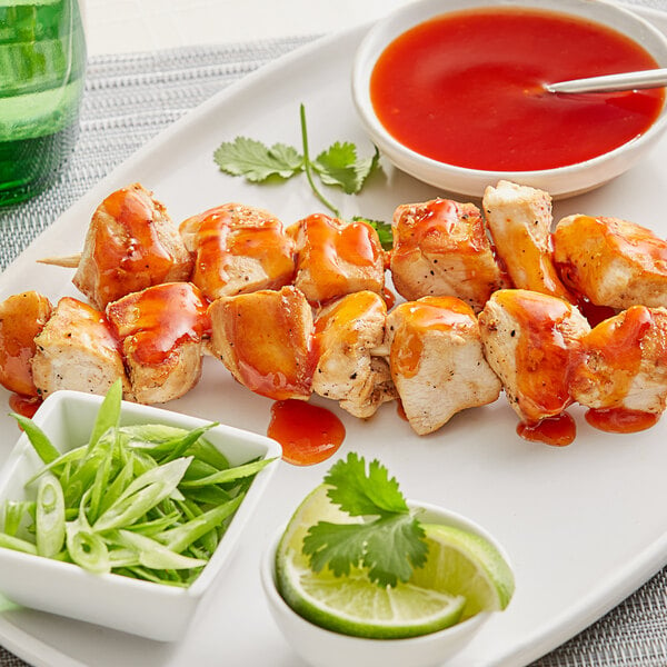 Chicken skewers with Sauce Craft Honey Sriracha sauce and green garnish on a plate.