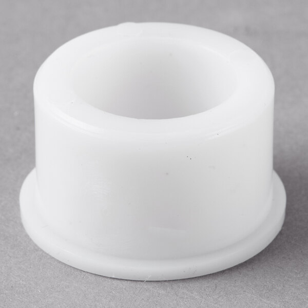 A white plastic Galaxy upper shaft bearing with a hole on a gray surface.