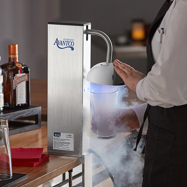 A person using an Avantco countertop glass froster to chill a drink.