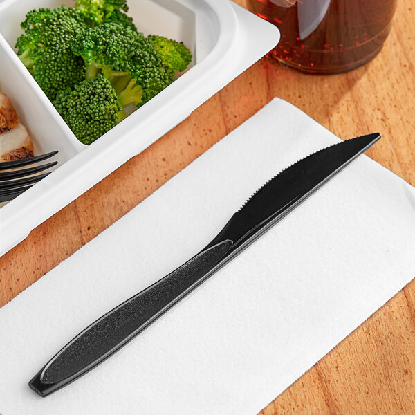 A black Solo Impress heavy weight plastic knife on a white napkin.
