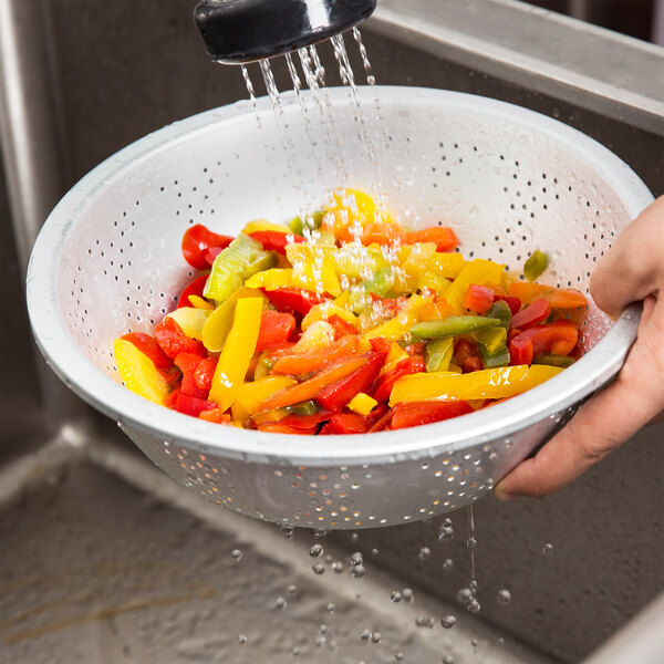 A person washing vegetables in a Thunder Group aluminum Chinese colander.