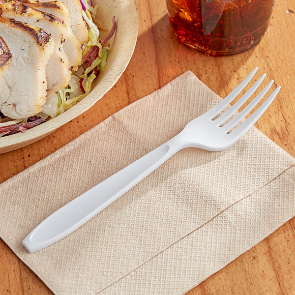 A Solo Impress white plastic fork on a napkin next to a bowl of food.