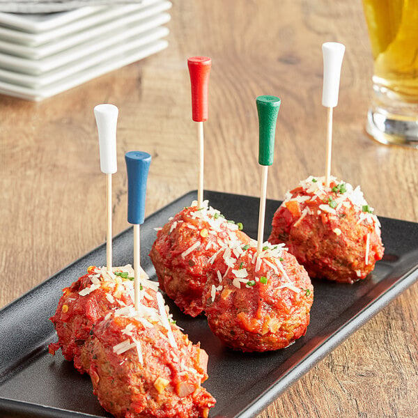 A plate of meatballs with cheese and sauce on Tablecraft bamboo picks.