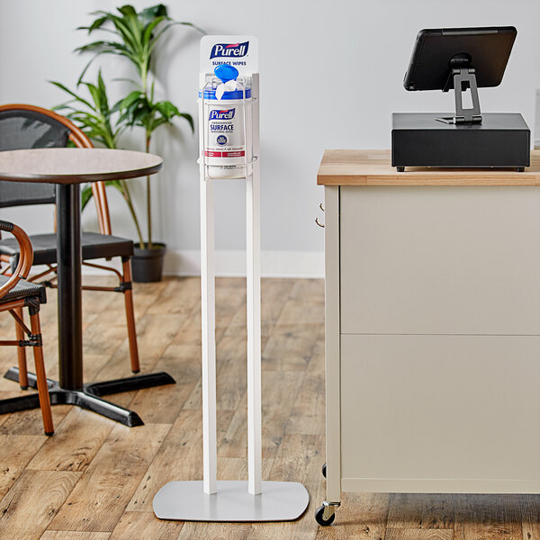 A white Purell surface wipes dispenser stand on a white counter.
