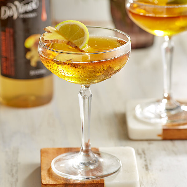 A glass of DaVinci Gourmet Spicy Ginger syrup with a lemon slice on the rim on a wooden tray.