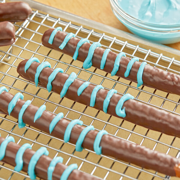 Chocolate covered pretzels coated in Alpine blue vanilla coating on a cooling rack.