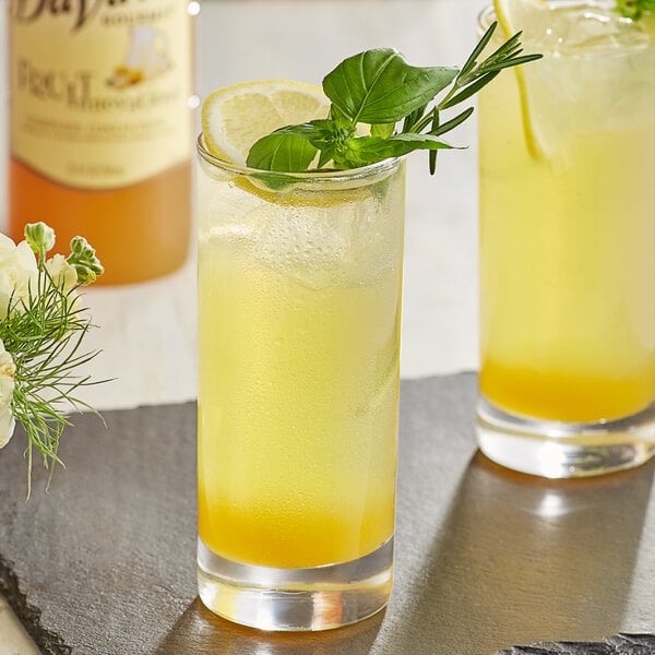 A glass of DaVinci Gourmet lemonade with a lemon slice and basil.