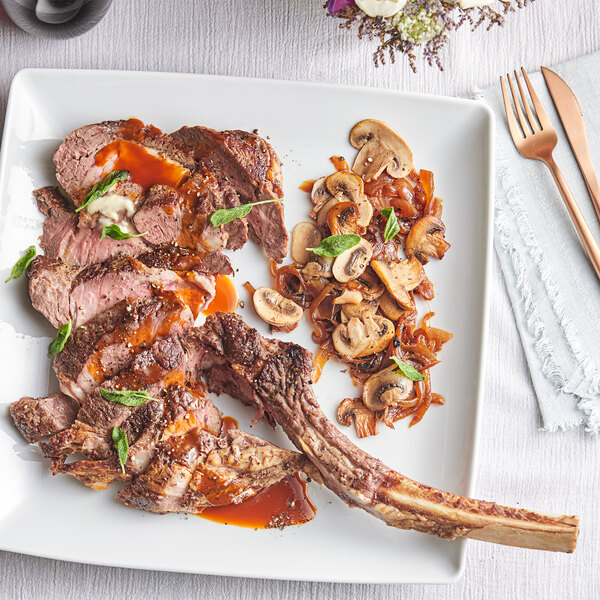 A plate with a TenderBison bone-in bison tomahawk ribeye steak served with mushrooms.